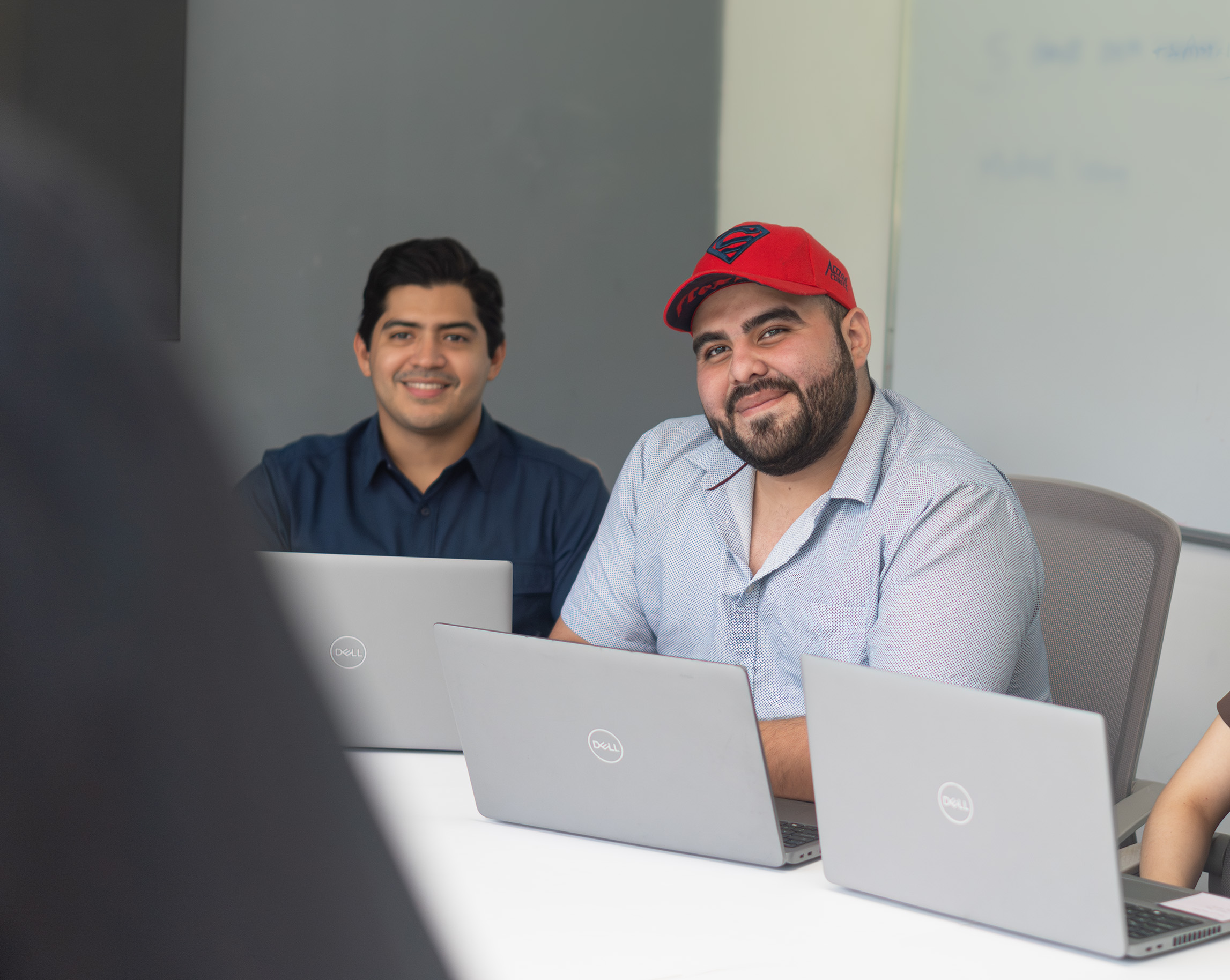 Two Work Ninjas colleagues laughing together over laptops in the office